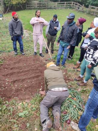 Campers learn from horticulturist/mycologist Brandon Morton how to plant garlic at the 2022 Black VegFest camping event at Liberation Farm.