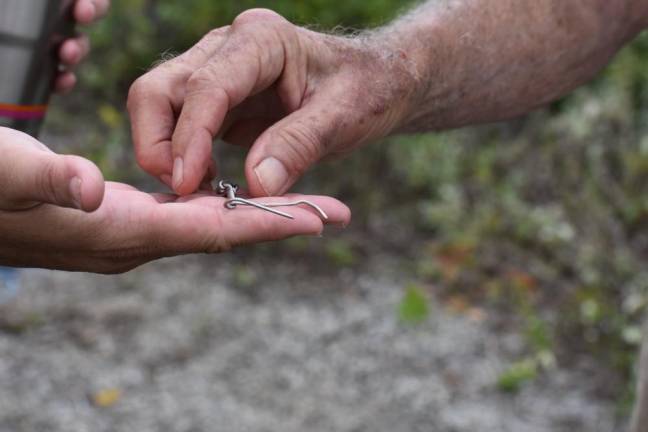 Howard takes a metal twist that Sweetman picked up, which once attached barbed wire to the chain link fence. Once you start looking, they’re everywhere.