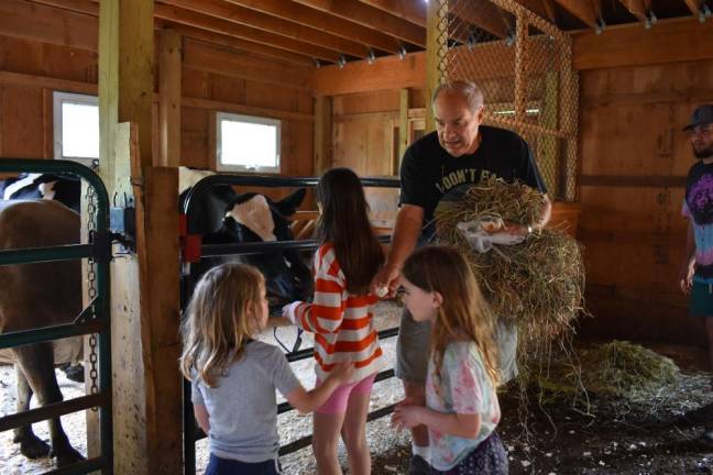 Bill Crain lets young visitors feed the cows a blueberry bagel, a particular favorite.