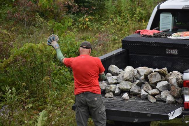 Volunteer Greg Galluccio of Warwick tosses aside concrete chunks that had held down the tarps atop the future pollinator meadow on Aug. 31.