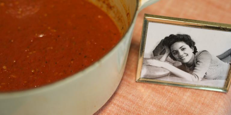 A pot of marinara next to a photo of Lorraine, who passed down the recipe to her daughter.