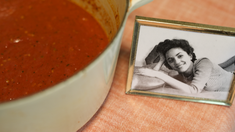 A pot of marinara next to a photo of Lorraine, who passed down the recipe to her daughter.